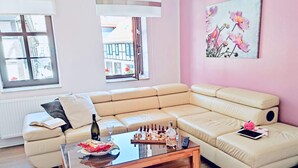 Una sala de estar moderna con un sofá seccional color beige, una mesa de centro de vidrio y un cuadro de flores en la pared.