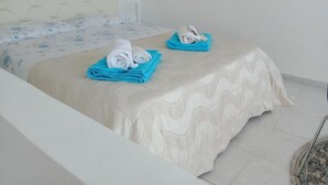 A hotel room with a bed, a smaller bed or sofa, and two blue towels on the smaller bed. - Holiday Home Near Pizzo Beach (Pizzo)