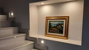 A staircase with a wall-mounted shelf displaying a framed painting. - Holiday Home Near Pizzo Beach (Pizzo)