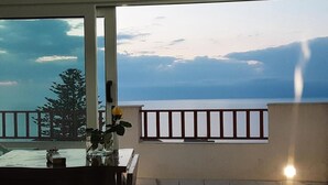 A balcony with a view of the sea, a table with a vase of flowers, and a chair. - Holiday Home Near Pizzo Beach (Pizzo)