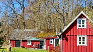 A red wooden house with a tiled roof, a fenced yard, and a clear sky. - 6 Person Holiday Home in Hishult (Hishult)