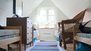 A cozy attic bedroom with a sloped ceiling, two beds, a dresser, a television, and a large window. - 6 Person Holiday Home in Hishult (Hishult)