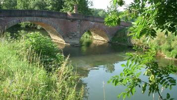 A stone bridge over a calm river with lush greenery around.