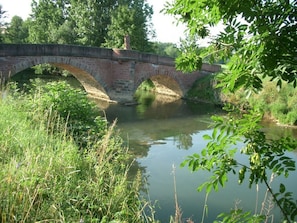 A stone bridge over a calm river with lush greenery around. - Tranquil Apartment Near Lake (Tauberbischofsheim)
