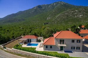 A villa with a swimming pool, stone walls, and a mountain backdrop. - Villa in Croatia With Stunning Mountain Views (Vrgorac)