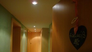 Un couloir avec un plancher en bois et des murs verts.