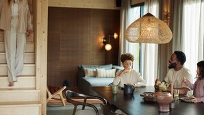 A modern interior with a dining area, wooden staircase, and a sofa in the background. - Apartment in Drenthe Near National Park (Appelscha)
