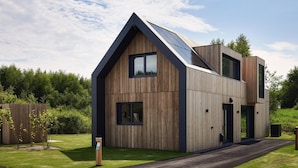 A modern two-story house with a sloped roof, large windows, and a solar panel installation. - Apartment in Drenthe Near National Park (Appelscha)