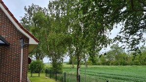 A brick building with a paved entrance and a fenced garden area. - Country House Country Idyll With Garden (Norden)