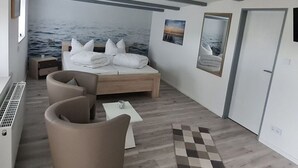 A modern bedroom with a bed, two armchairs, a small table, and a view of the sea through a large window. - Country House Country Idyll With Garden (Norden)