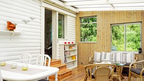 A cozy room with a white table, wicker chairs, a bookshelf, and large windows offering a view of the greenery outside. - 10 Person Holiday Home in Brastad-by Traum (Brastad)