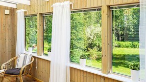 A room with wooden walls, large windows, and a wicker chair. - 10 Person Holiday Home in Brastad-by Traum (Brastad)