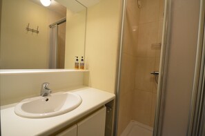 A bathroom with a white sink, a mirror, and a shower area. - Perfect Apartment Near Dunes (Koksijde)