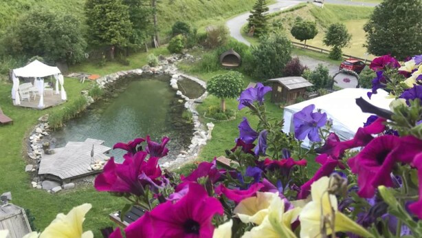 Un jardin agrémenté d’un bassin, d’un kiosque et de nombreuses variétés de fleurs.