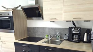 Une cuisine moderne équipée d’un four encastré, d’un four à micro-ondes, d’une machine à café et d’un évier.