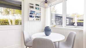 A dining area with a round table, four grey chairs, a blue vase, and a pendant light. - Tranquil Retreat on Eno - By Traum Ferienwohnungen (Karrebæksminde)