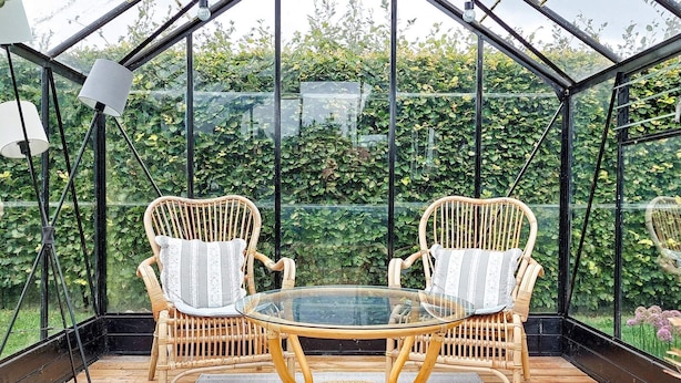 A glass-enclosed patio with wicker furniture and a glass table. - Tranquil Retreat on Eno - By Traum Ferienwohnungen (Karrebæksminde)