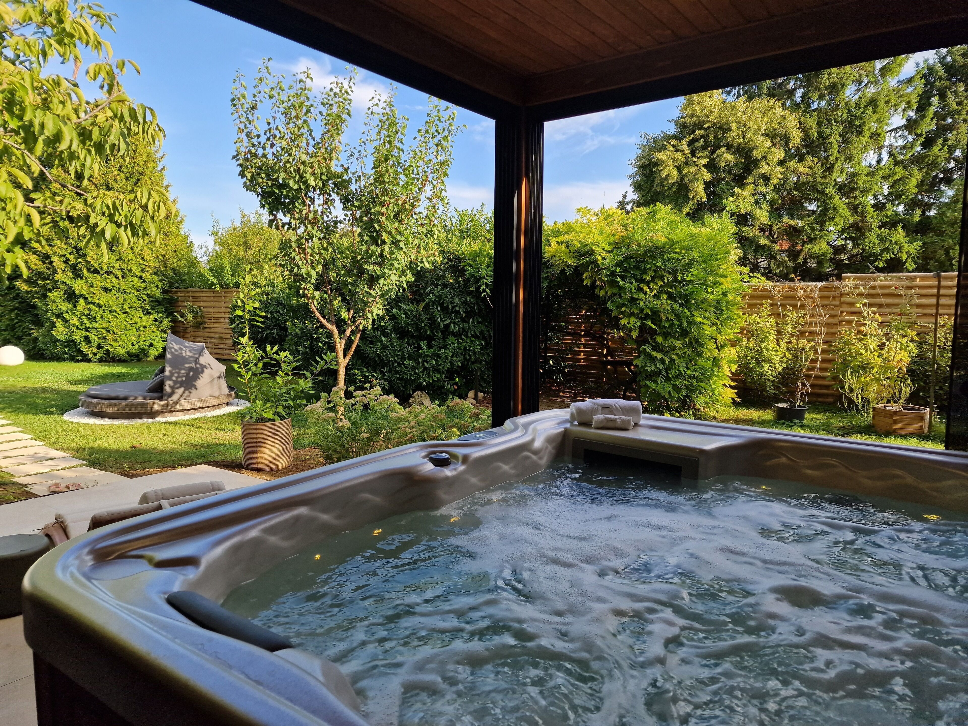 A hot tub with a view of a lush garden and a wooden deck.