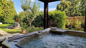 A hot tub with a view of a lush garden and a wooden deck.