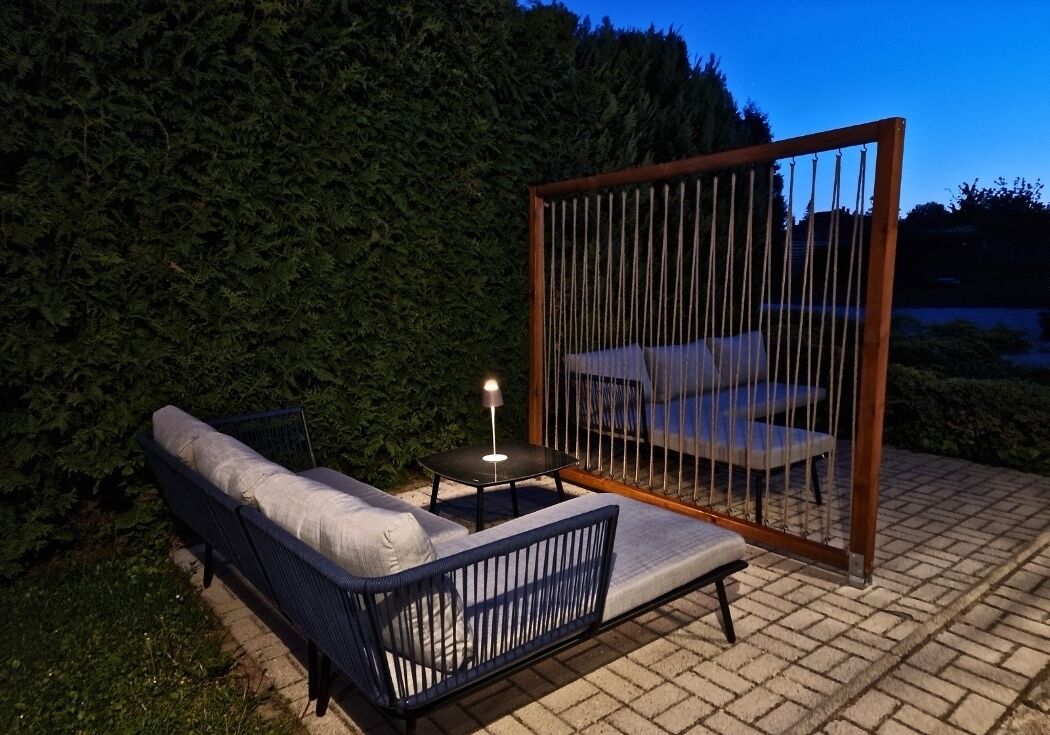 An outdoor seating area with a sofa and a table, enclosed by a wooden fence.