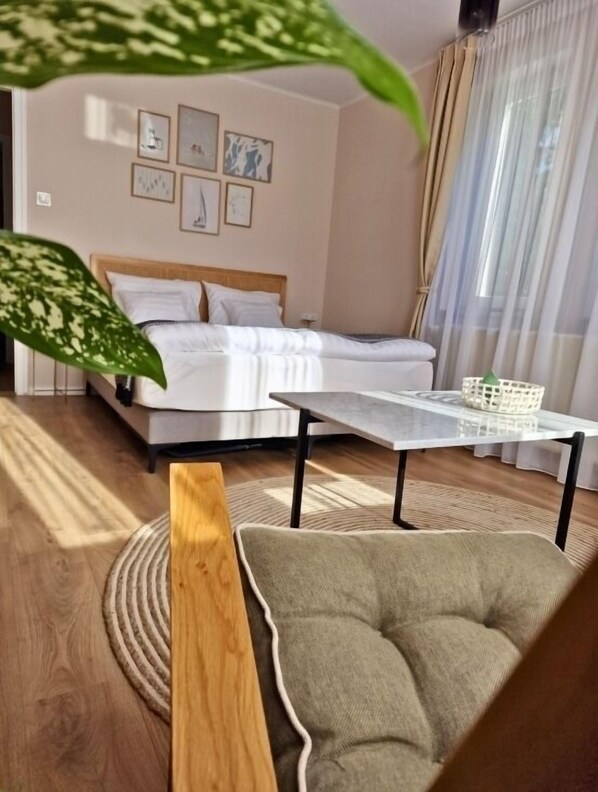 A modern bedroom with a bed, a bedside table, a chair, and a window with curtains.