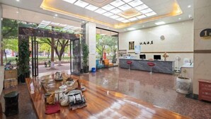 Un espace d’accueil d’hôtel doté d’une cloison en verre, d’un comptoir de réception et d’une enseigne indiquant le nom de l’hôtel.