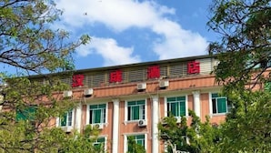 Un bâtiment surmonté d’une enseigne rouge et entouré d’arbres.