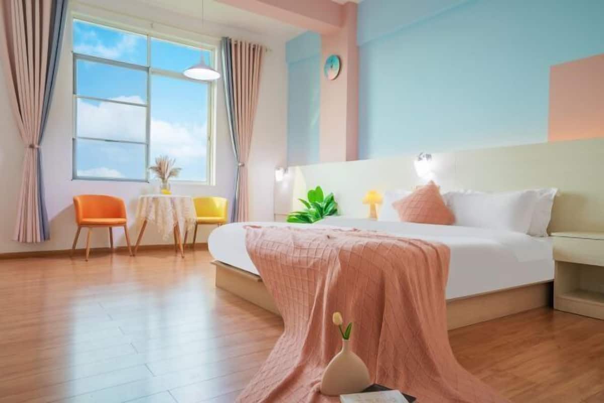 Un dormitorio con una cama, una mesita de noche, una silla, una ventana y una planta.