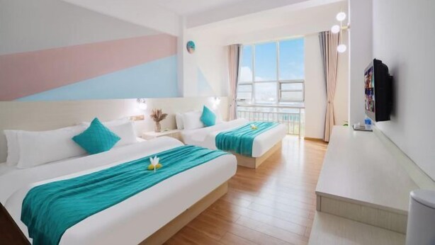 Une chambre d’hôtel avec deux lits, une télévision, un bureau et un balcon avec vue.