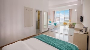 Une chambre d’hôtel comprenant un lit, un bureau, une chaise, une fenêtre donnant sur un paysage agréable et une porte menant à une autre pièce.