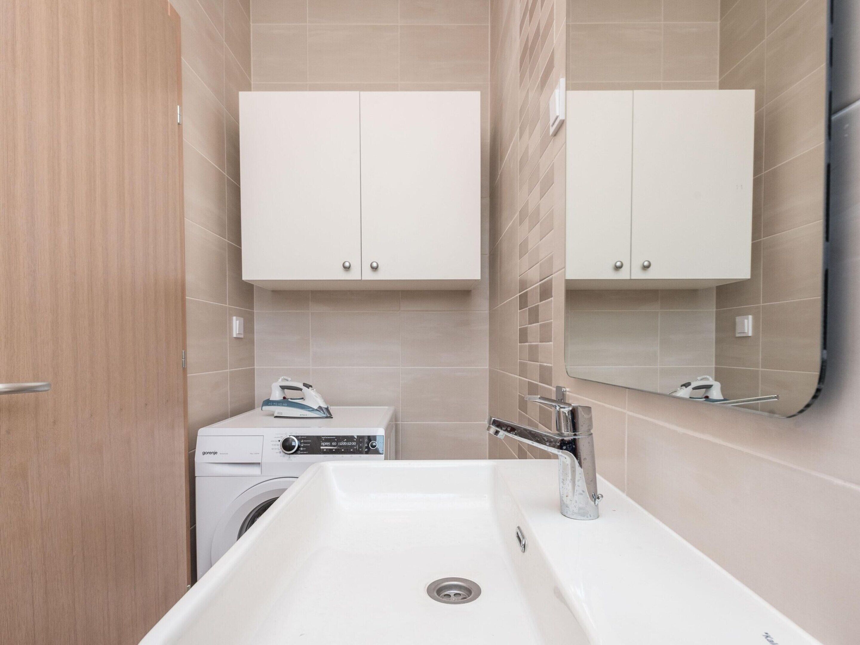 Une salle de bain moderne avec un lavabo blanc, un miroir et deux armoires au-dessus.