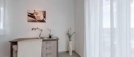 A minimalist office space with a desk, chair, and two potted plants.