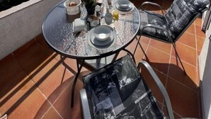 A terrace with a round table set for dining, outdoor chairs, and a view of the sea and a white house in the background. - Appartement Lady Daniela (Lovran)
