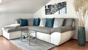 A modern living room with a sectional sofa, a glass coffee table, and a decorative vase with pampas grass. - Appartement Lady Daniela (Lovran)