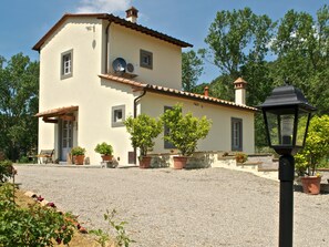 A two-story building with a tiled roof, potted plants, and a gravel driveway. - Belvilla by OYO Barbagianni (Cortona)