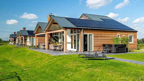 Une rangée de maisons modernes dotées de panneaux solaires, de façades en bois et d’espaces de détente extérieurs.