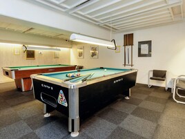 Ein Billardtisch mit Schwarz-Weiß-Muster, im Hintergrund ein weiterer Billardtisch und ein Stuhl zur Rechten.
