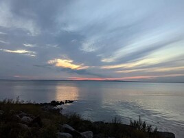 Una masa de agua tranquila con una costa rocosa y un cielo nublado.