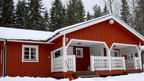 A red wooden house with a white porch and a snow-covered roof. - 4 Person Holiday Home in Torsby (Torsby)