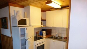A compact kitchen with white cabinets, a microwave, a stove, and a sink. - 4 Person Holiday Home in Torsby (Torsby)