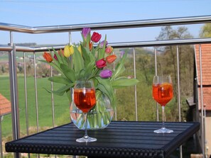 A balcony with a metal railing, a black table, and two glasses of red beverage. - Penthouse Tauberblick Terrace (Tauberbischofsheim)