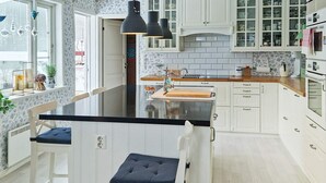 A kitchen with white cabinetry, a black countertop, and a central island with bar stools. - 9 Person Holiday Home in Tjodalyng-by Traum (Larvik)