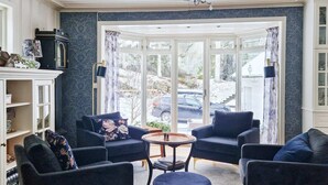 A modern living room with dark armchairs, a round coffee table, and a large window with curtains. - 9 Person Holiday Home in Tjodalyng-by Traum (Larvik)