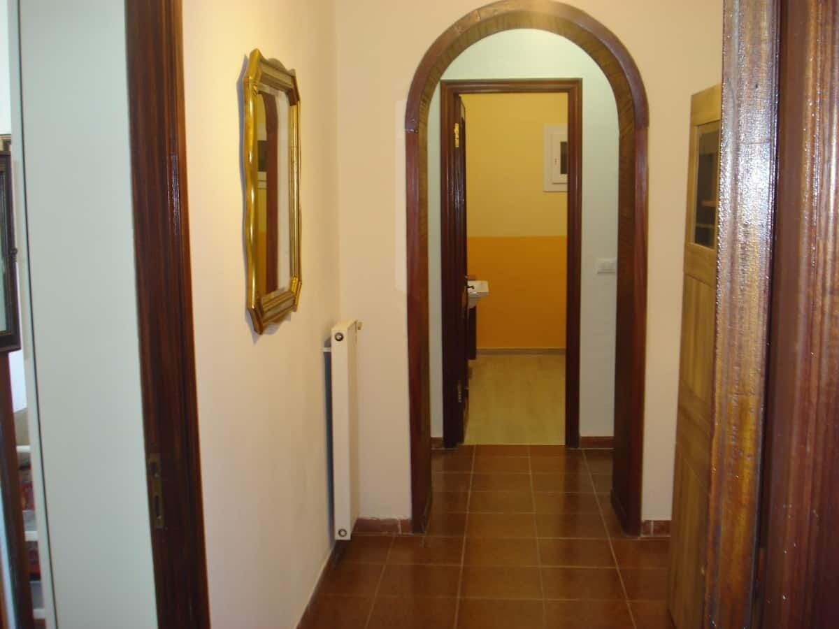 Un couloir avec un cadre de porte en bois, un radiateur et un miroir accroché au mur.