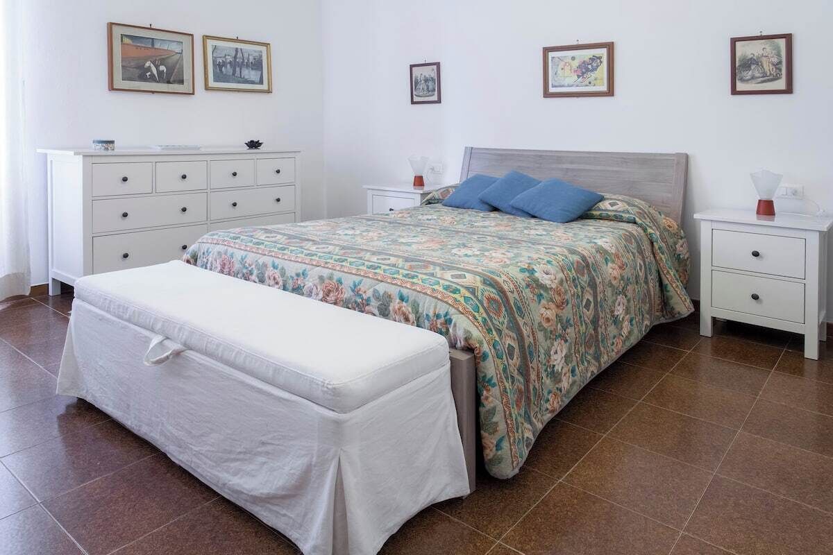 A bedroom with a bed, a bench, a dresser, and a nightstand.