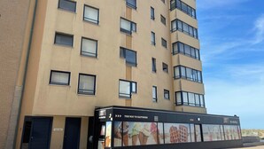 A building with multiple floors, a cafe named "Cafe Hartmann" on the ground floor, and an ice cream shop named "Linny's" with a sign advertising "Ice Creams & Waffles". - Apartment in Nieuwpoort With sea View (Nieuwpoort)