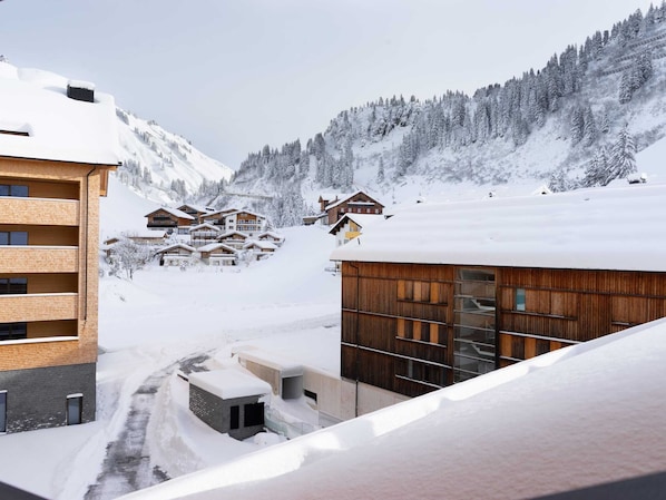 A snow-covered mountain village with wooden buildings and a ski slope.