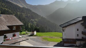 Un village de montagne aux maisons traditionnelles, doté d’un petit jardin et offrant une vue dégagée sur les montagnes environnantes.