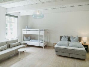 Ein modernes, minimalistisches Schlafzimmer mit Etagenbett, Sofa und Bett.