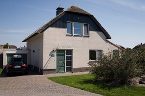 A house with a thatched roof, a garage, and a car parked in front. - Beautiful Villa With Conservatory (Makkum)